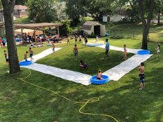 a group of people playing in a yard with an inflatable pool on the grass