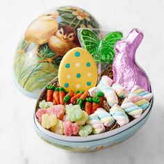 an easter basket filled with candy, candies and a painted egg sitting on top of it