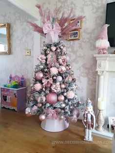 a pink and silver christmas tree in a living room with ornaments on the top,