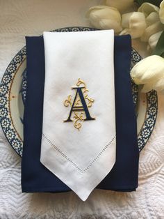 a napkin with the letter a on it sits next to a plate and flower arrangement