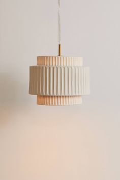 a white lamp hanging from a ceiling with a light fixture on it's side