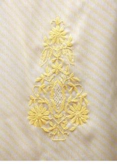 an embroidered piece of cloth with yellow flowers and leaves on white fabric, closeup