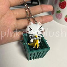 a hand holding a keychain that has a cat in the basket on it