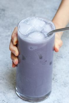 a person holding a glass with ice in it and a spoon sticking out of it