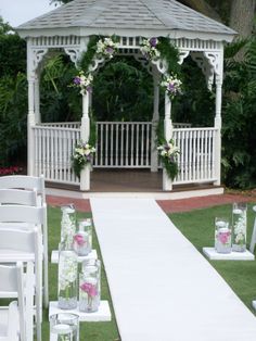 an outdoor wedding setup with white chairs and flowers