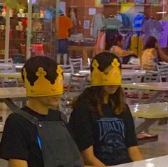 two people wearing crowns sitting at tables