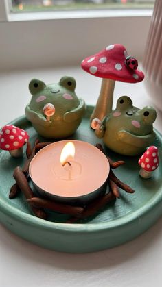 a candle is lit on a plate with little toad figurines and mushrooms around it