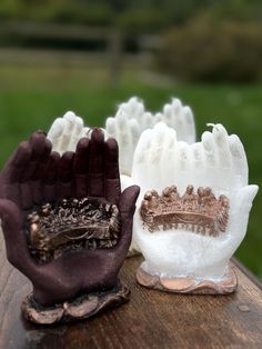 three gloves with crowns on them sitting on a wooden table in front of some grass