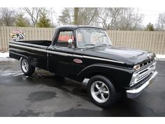 an old black pickup truck parked in a parking lot