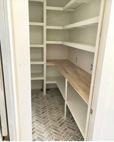 an empty walk in closet with white shelving and wooden shelves on either side of the door