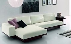 a modern living room with white furniture and pictures on the wall above it's couch