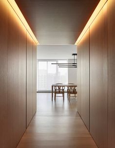 an empty hallway with wooden walls and tables in the center is lit by recessed lighting