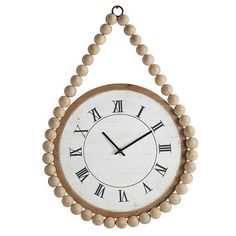 a clock hanging from the side of a wall with beads on it's face