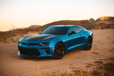 a blue chevrolet camaro is parked in the desert