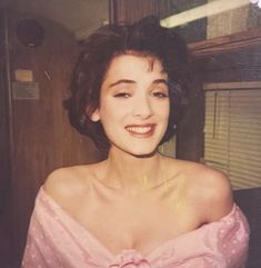 an old photo of a woman in a pink dress smiling at the camera with her eyes closed