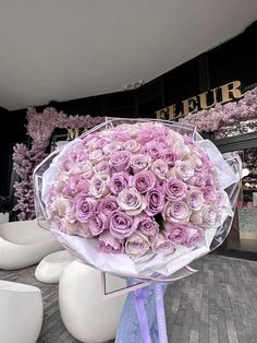 a large bouquet of pink roses sitting on top of a white chair in front of a store