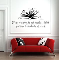 a red couch sitting in front of a white wall with a book quote on it