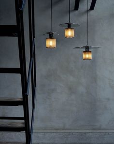 three lights hanging from the ceiling in a room with stairs and ladders next to it