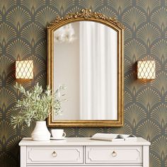 a white dresser sitting under a mirror next to a vase with flowers on top of it