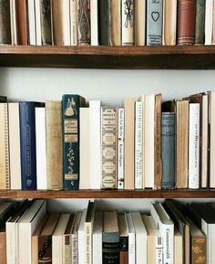 books are lined up on wooden shelves in a room with white walls and wood flooring