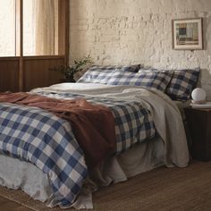 a bed with blue and white checkered sheets in a room next to a window