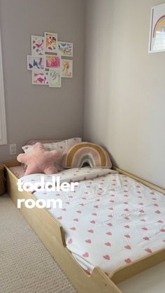 a child's bed with pink hearts on it in a room that has white carpet and gray walls