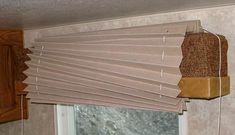 a cat sitting on top of a window sill in front of a curtained window