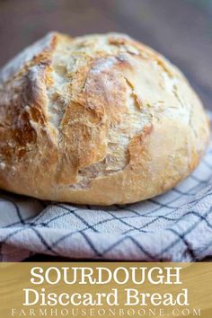 a loaf of bread sitting on top of a wooden table next to a blue and white towel