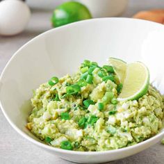 a white bowl filled with guacamole and topped with a slice of lime