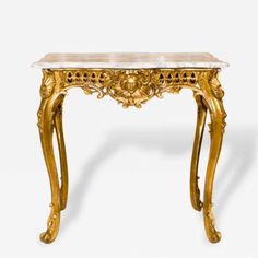 an antique console table with marble top and gold leaf decoration on the legs, against a white background