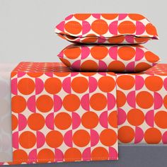 two orange and pink polka dot boxes stacked on top of each other, with one in the middle