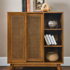 a wooden cabinet with books and vases on top