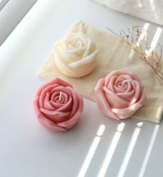 two pink and white roses sitting on top of a piece of paper next to each other