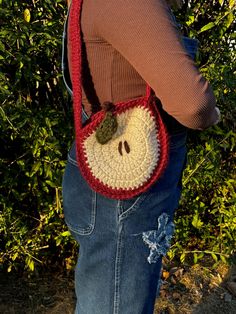 a woman is holding a crocheted bag with a smiley face on the front