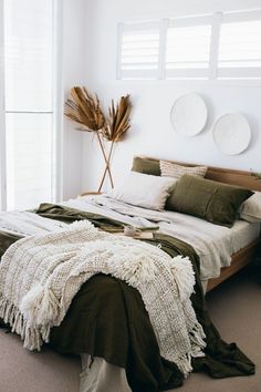 a large bed sitting in a bedroom next to a tall plant on top of a wooden headboard