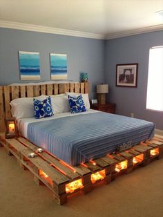 a bed made out of wooden pallets with candles on the bottom and pillows on top