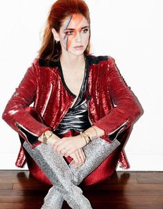 a woman sitting on top of a wooden floor with her legs crossed and painted red