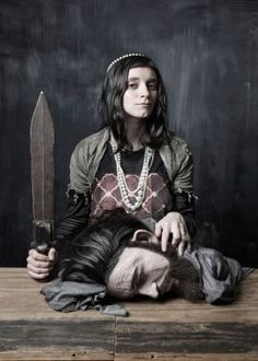 a woman sitting on top of a wooden table holding a knife