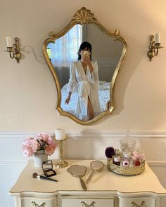 a woman is taking a selfie in front of a mirror on a dresser next to flowers