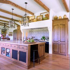 a kitchen with wooden cabinets and an island in the middle, surrounded by wood flooring