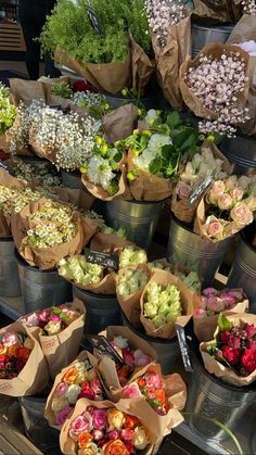 many different types of flowers are on display in buckets at the farmers'market