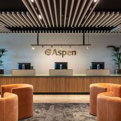 an office lobby with chairs and desks in front of the reception counter that says aspen