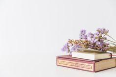 an open book sitting on top of a table with purple flowers growing out of it