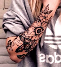 a woman's arm with sunflowers and leaves tattooed on the side of her arm