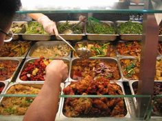 a man standing in front of a display case filled with lots of different types of food