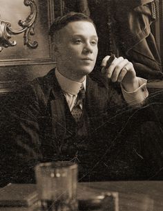 a man in a suit and tie sitting at a table with a glass on it