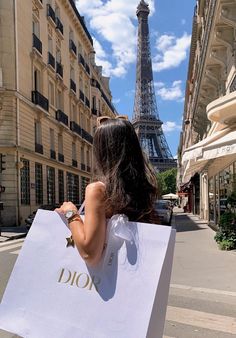 a woman carrying a shopping bag in front of the eiffel tower