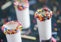 three white cups filled with sprinkles on top of a table