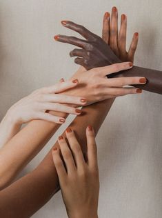 four hands reaching up to each other with their fingers extended out and one hand on top of the other