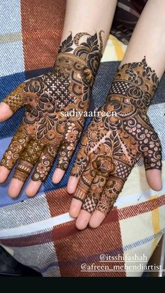 two hands with henna tattoos on them, one is showing off the intricate design